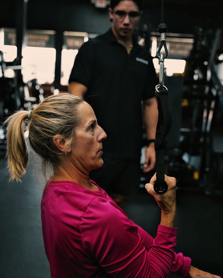 Coach watching a client's form on a cable row